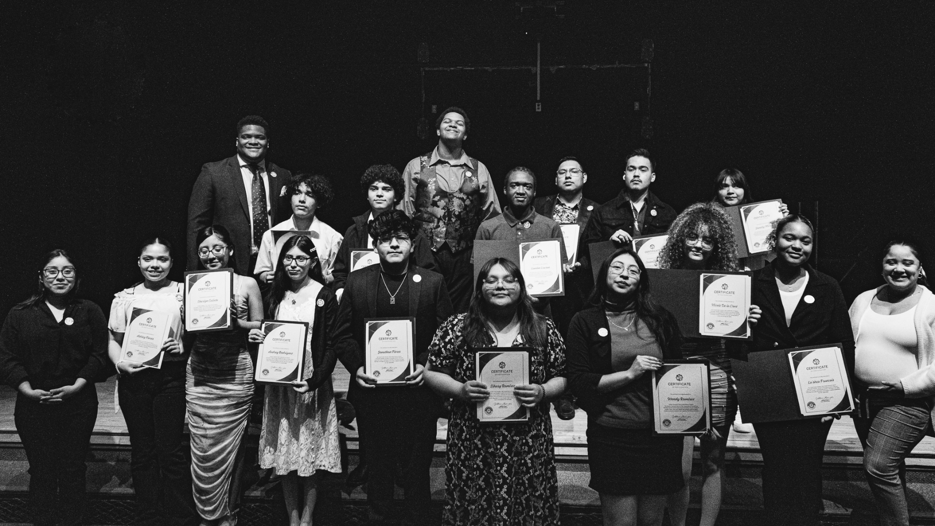 Students and staff holding certificates on stage after a Shift and Succeed event