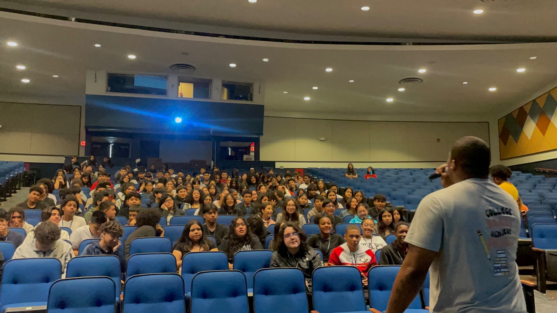 Speaker addressing a full auditorium of students